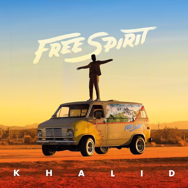 Khalid stands on top of a van in front of a desert landscape in the sunset sky.