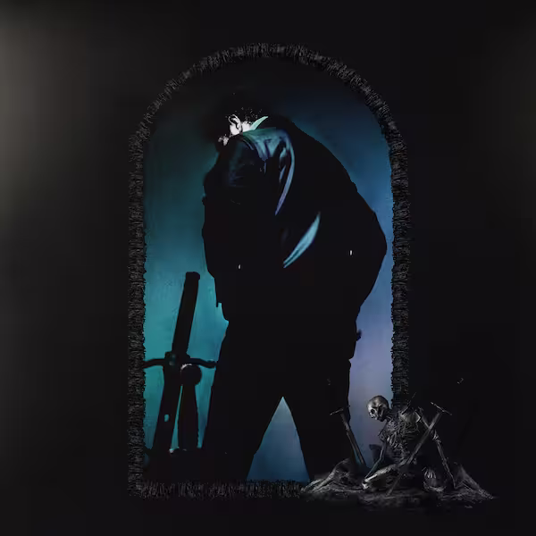 Malone turns his back against the viewer wearing a black jacket and pants. He stands inside a mural with bones and a sword beside him.