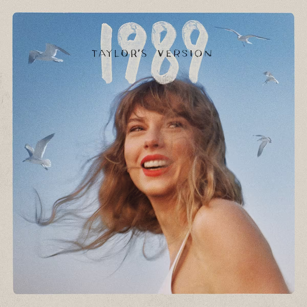 Taylor Swift looks to her left smiling. The background is a blue sky with seagulls flying.