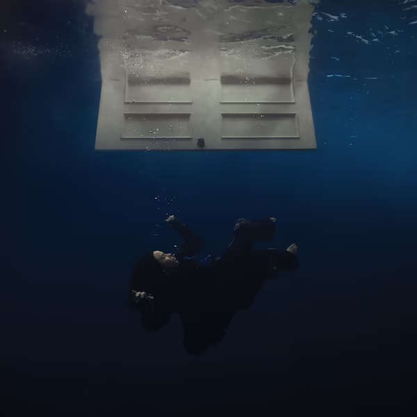 In the dark depths underwater, a clothed Billie Eilish sinks. At the top, a white door on the surface opens downwards.